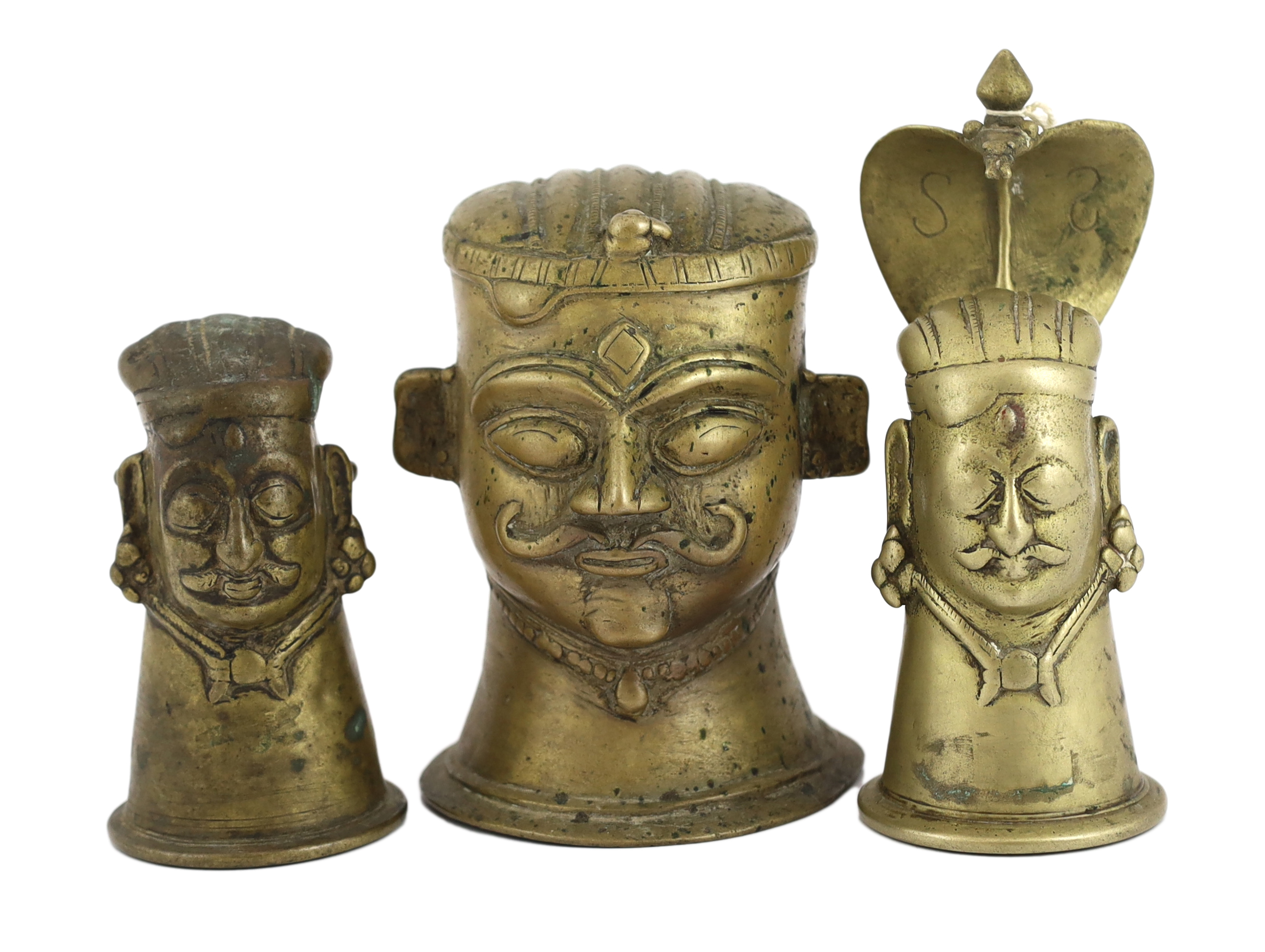 A group of three brass alloy Shiva Mukhalingam, Southern India, 16th-18th century, each depicting a Shiva head, wearing his characteristic moustache, earrings and matted hair, one example surmounted by a removable Naga (